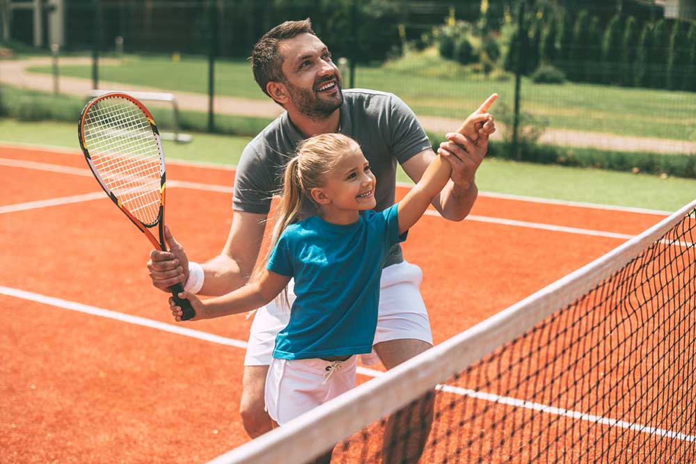 father and daughter playing tennis