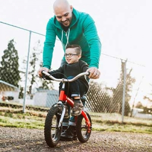 father teaching son to ride bicycle 