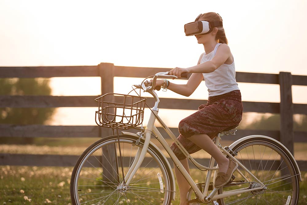 Girl riding bike wearing virtual reality goggles