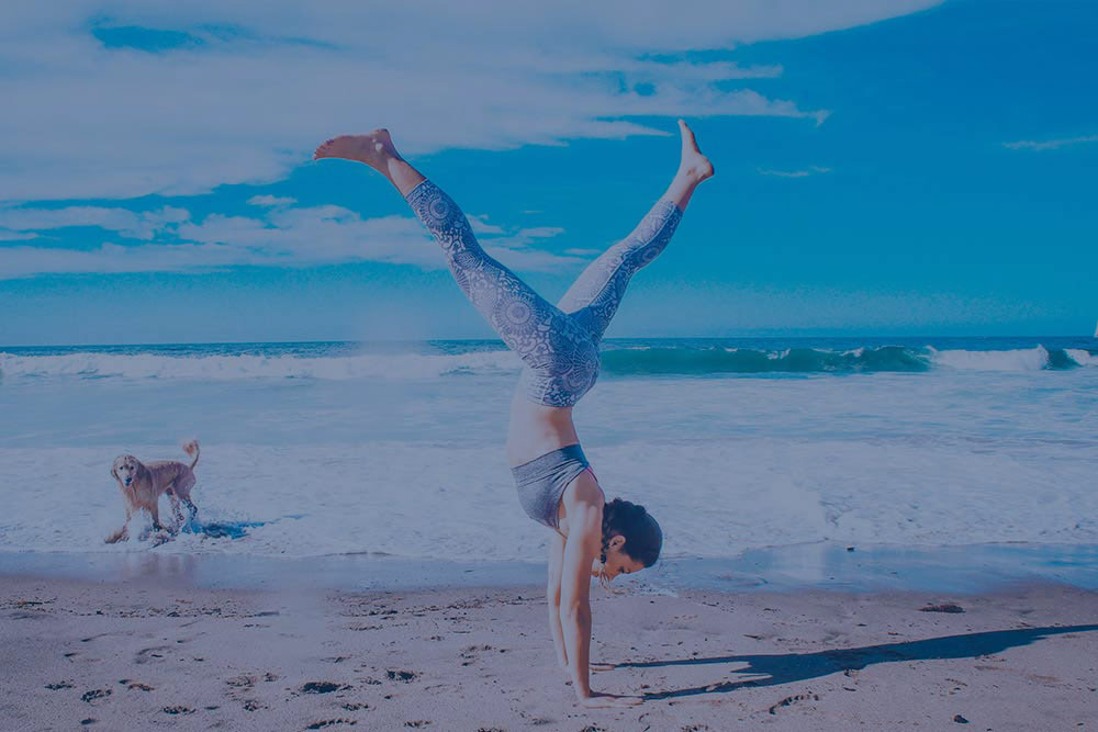 woman doing a handstand on the beach