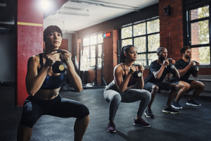 Two men and two women using kettlebells for a workout in a gym