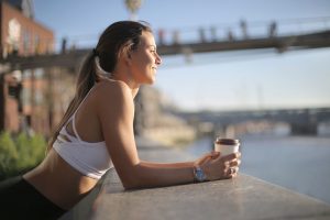 Woman athlete drinking coffee overlooking water