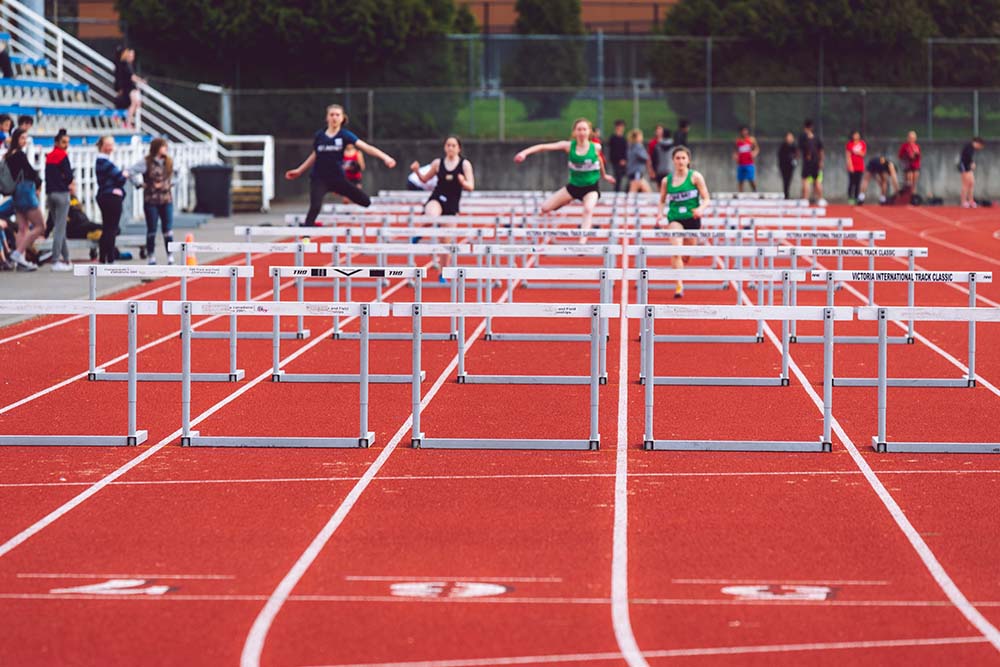 Sprinters doing the hurdles on a track
